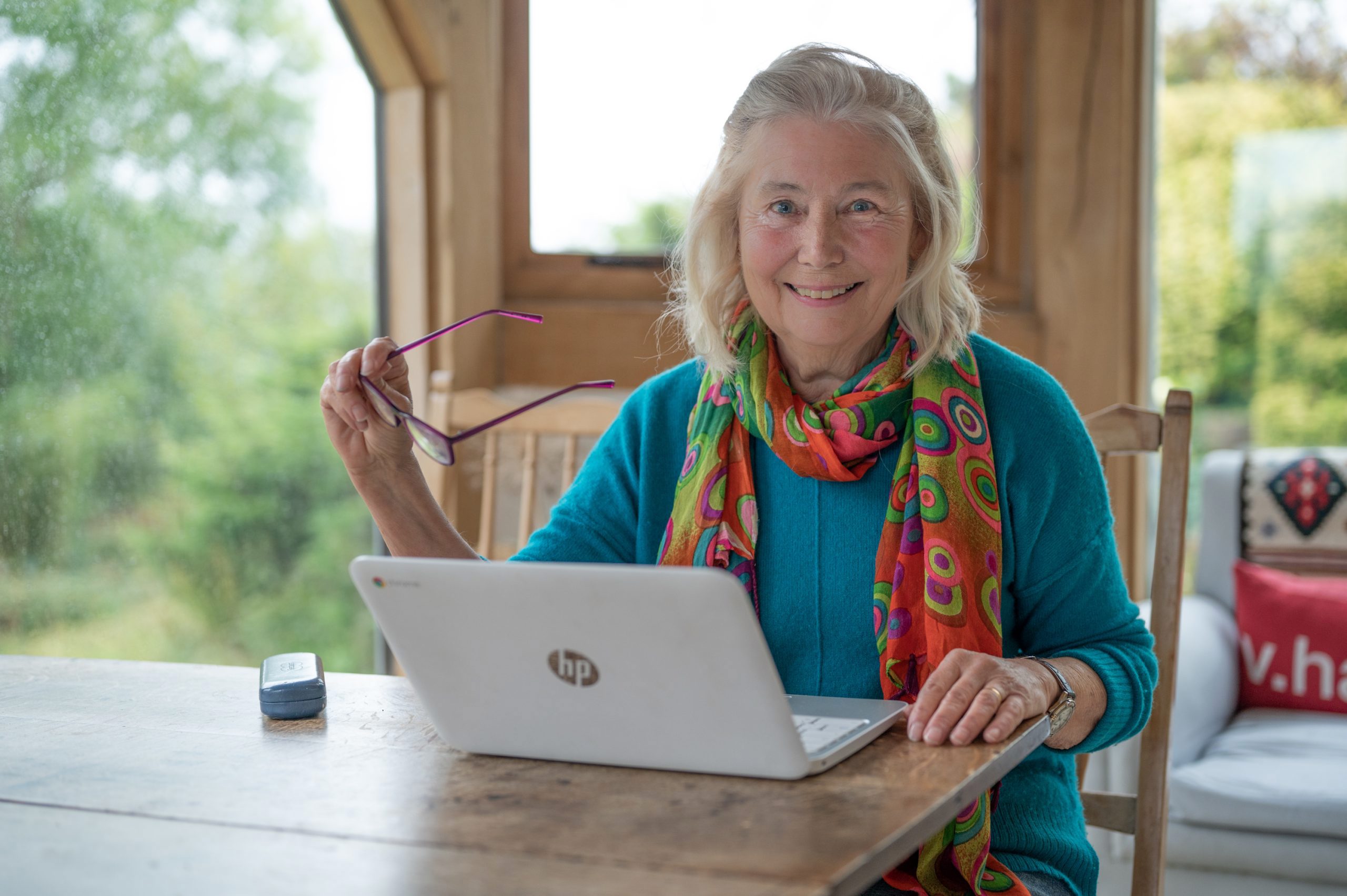 A woman sitting at a table with a laptop, working on her computer.