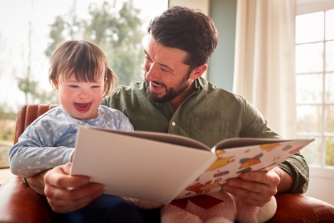 Smiling child enjoying picture book with dad