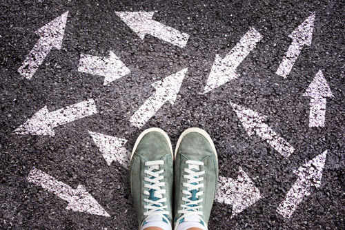Two feet standing on a playground with chalk arrows in all directions