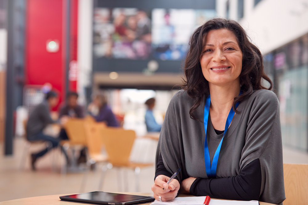 A smiling woman wearing a blue lanyard