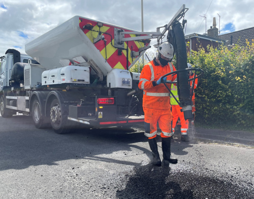 Photo of asphalt being sprayed into a pothole with a spray injection patcher