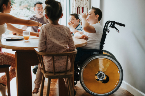 child in wheelchair having dinner with family