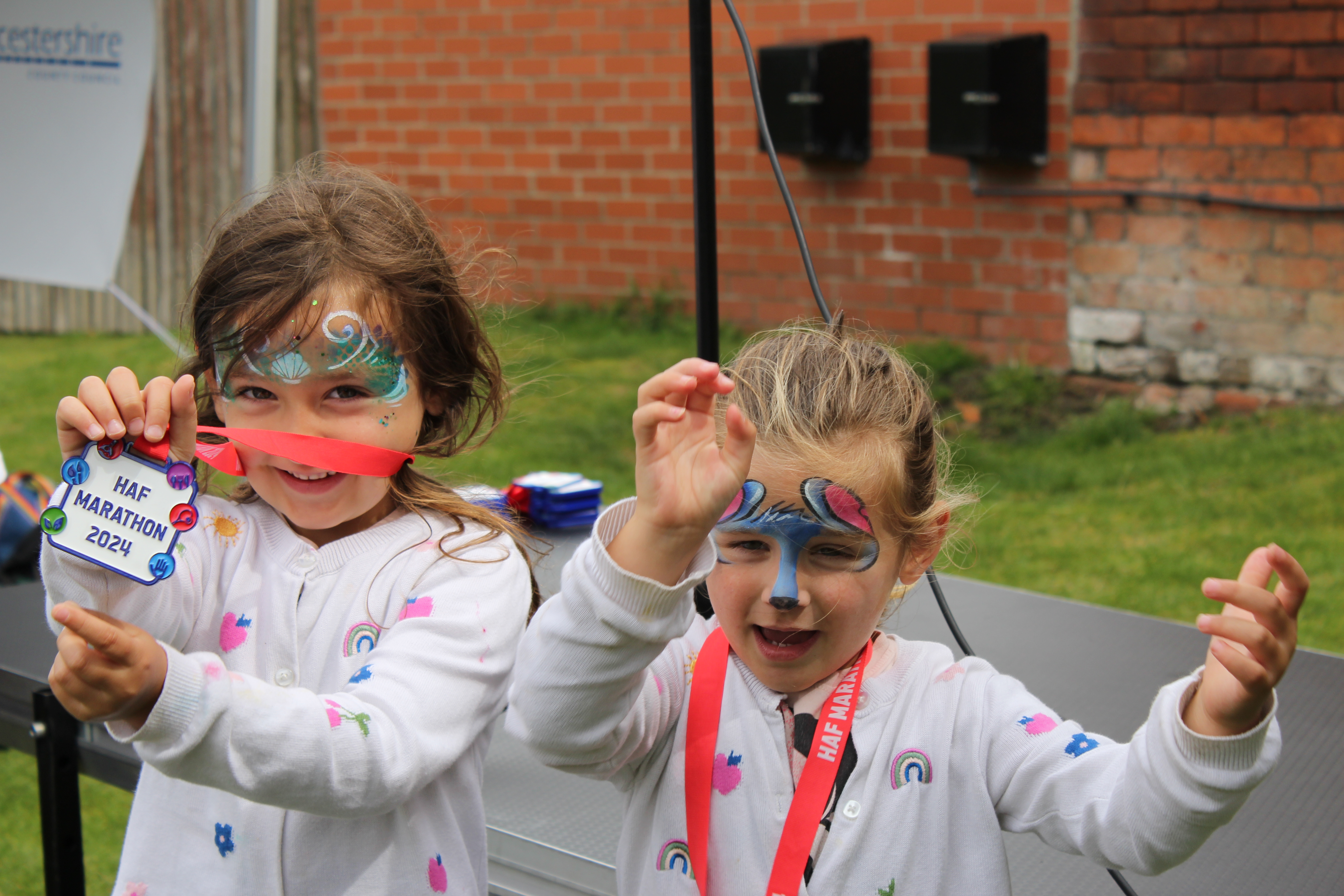 Two happy girls with face painted and haf medal