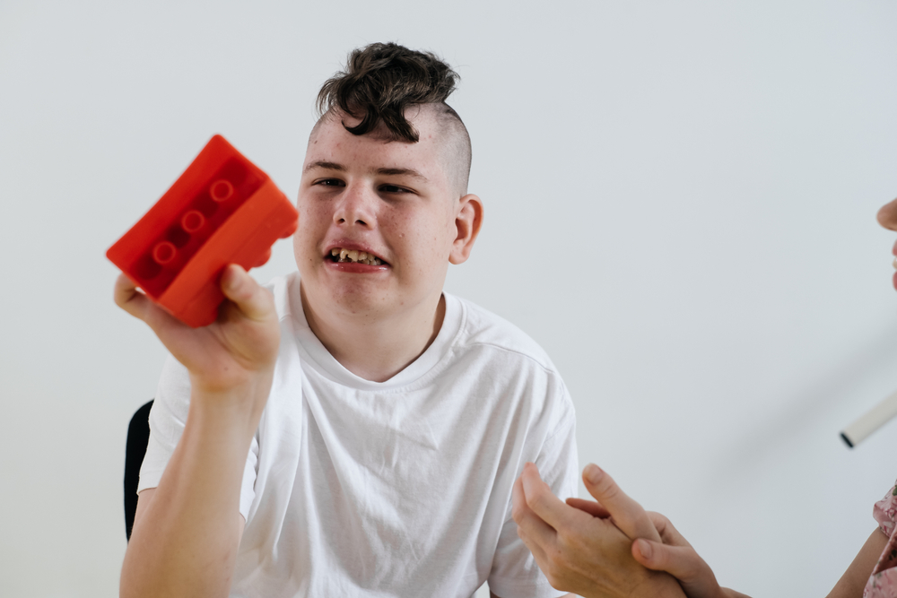 Teenage boy smiling and holding a red building block