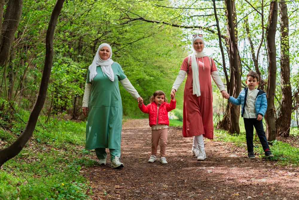 Two women walking with children through woodland on on a sunny day