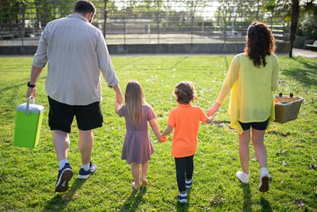 parents and two children hold hands on a walk outside