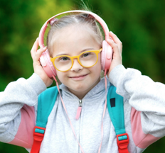 Primary-aged girl wearing headphones, yellow glasses and smiling