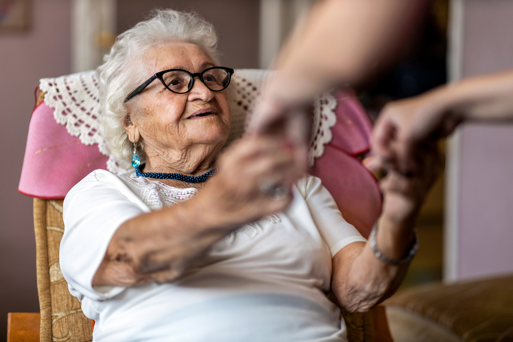 senior woman is supported to stand up from a chair