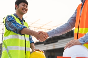 A male builder in uniform shaking someone's hand.