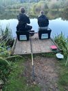 Two young people by a river bank fishing
