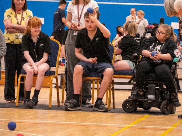 A group of individuals playing Boccia, with one wheelchair user.