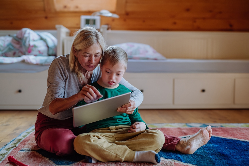 Child With Disability Sits On Mat With Parent