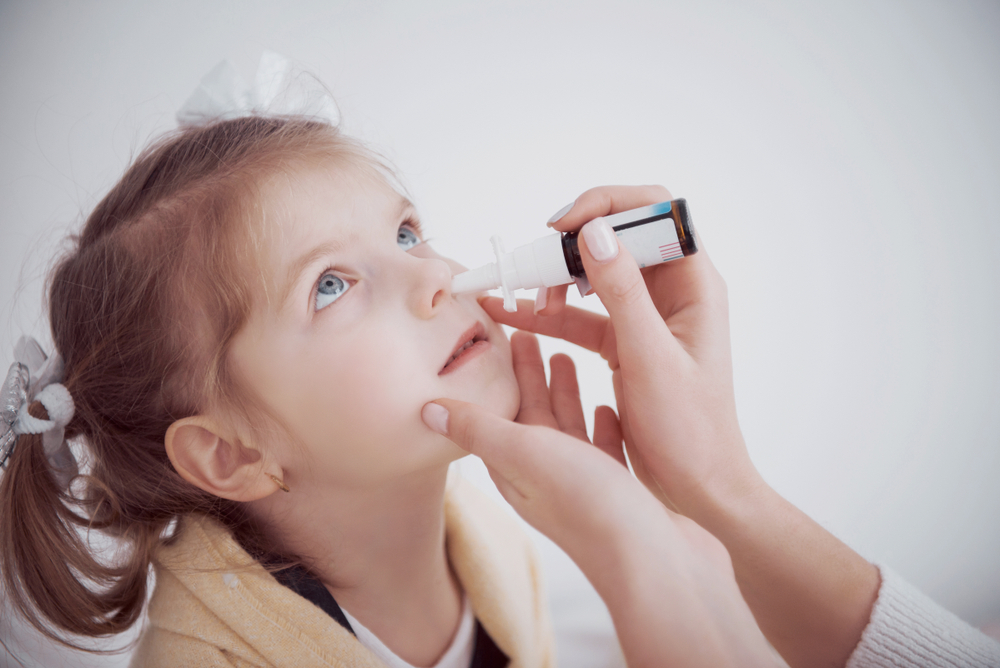  Child receiving nasal vaccination from an adult