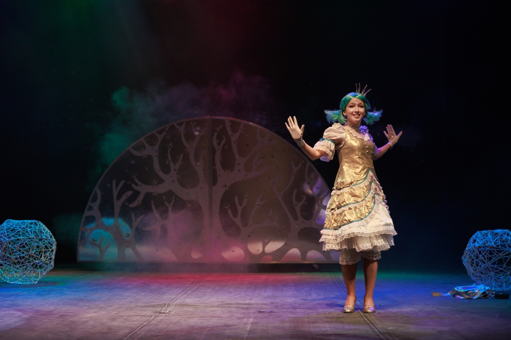 Girl in winter princess costume poses on a stage